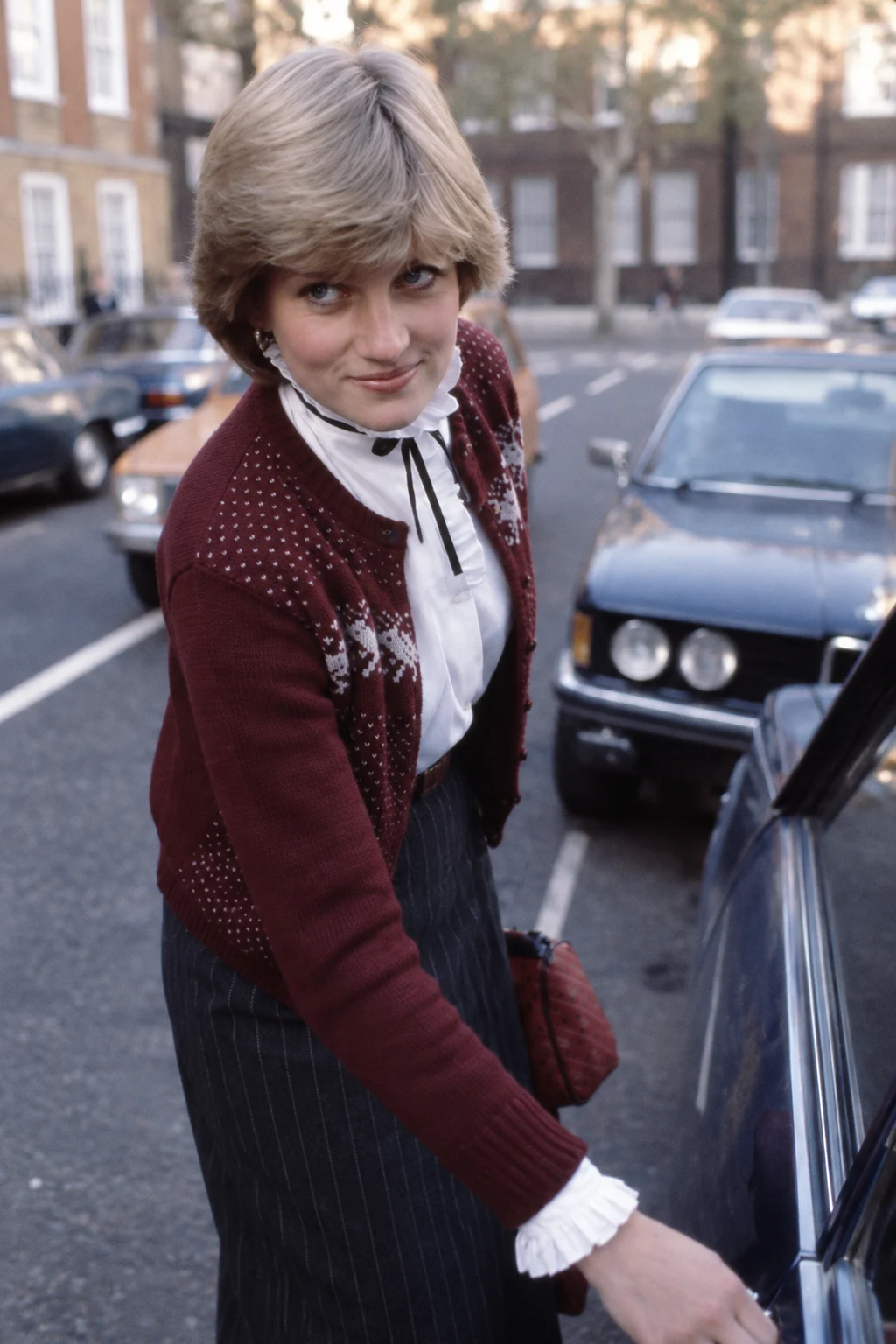 ワイン色のカーディガンと白いフリルブラウスを着た1980年のダイアナのルック再現